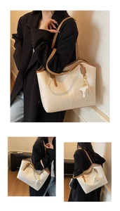 Detail of a large cream and brown tote bag with elephant charm in a casual office style