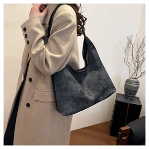 Detalle del bolso hobo de cuero esmerilado gris oscuro con costuras blancas en la bandolera