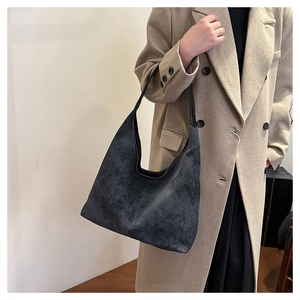 Detalle de bolso hobo de ante gris con costuras en contraste sobre abrigo beige