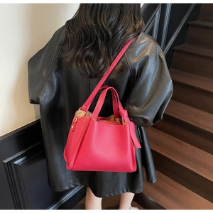 Dettaglio della borsa rosso rosa in pelle martellata con finiture dorate e tracolla