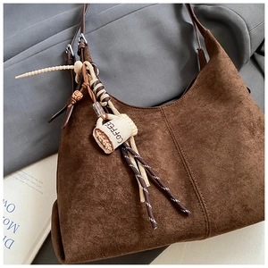 Detail of brown suede tote bag with distinctive stitched seam and coffee woven charm