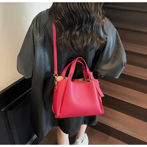 Borsa a secchiello magenta con motivo lychee indossata a tracolla in stile urbano