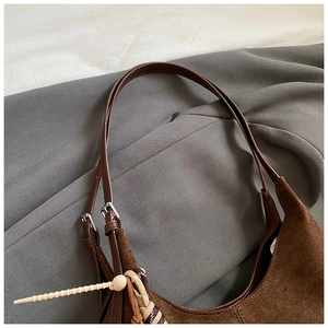 Detail of vintage brown suede tote shoulder strap with metal buckle and woven tassel