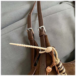 Detail of retro brown suede tote showing fine matte texture and silver metal buckles