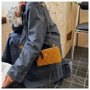 Detail of yellow quilted crossbody bag featuring golden camellia clasp and chain strap