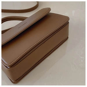Détail du sac à bandoulière en cuir marron montrant les coutures et l'épaisseur du côté