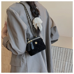 Detail of black velvet crossbody bag with gold flower logo and leather chain strap