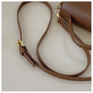 Détail de la bandoulière réglable en cuir marron avec boucle dorée sur un sac à main chic