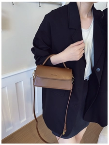 Détail du sac à main en cuir marron caramel avec logo embossé et poignée rigide