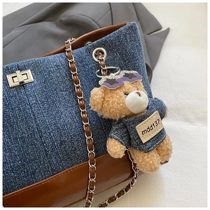 Detail of denim and leather contrast tote with silver clasp and plush bear charm