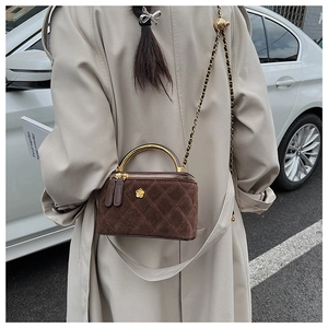 Brown quilted suede crossbody bag with gold floral clasp and chain strap on a model