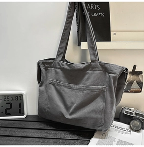 Detailed view of the dark grey canvas tote bag with front pocket in a lifestyle setting
