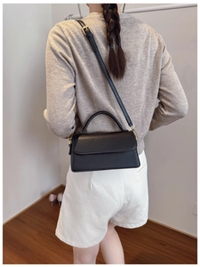 Vue détaillée du sac à main noir montrant la bandoulière réglable et la texture du cuir
