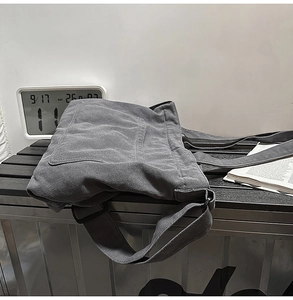 Close-up of deep grey washed canvas tote bag with large front pocket on metal bench