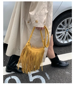 Close-up of bohemian yellow fringe shoulder bag with long suede tassels in street style