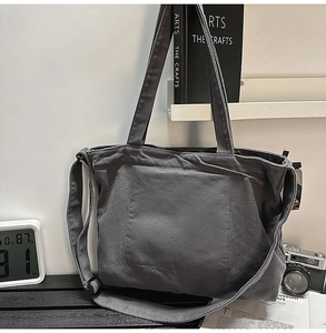 Dark grey canvas tote bag with adjustable shoulder strap shown in a lifestyle setting
