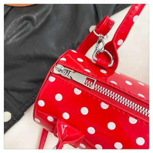 Gros plan du sac cylindrique rouge à pois avec cuir verni brillant et fermeture éclair argentée