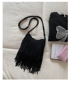 Detailed flat lay of a black bohemian crossbody bag with long fringe and suede texture