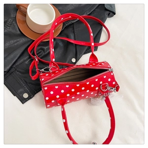 Détail du sac cylindrique en cuir verni rouge à pois blancs et fermeture éclair argentée
