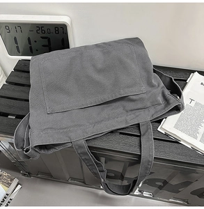 Detail of dark grey heavy canvas tote bag with large front pocket on a wooden bench
