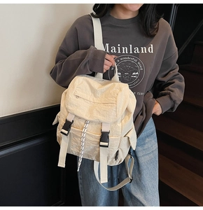 Mochila de nailon beige con cordón y hebillas mostrada por una modelo en exteriores