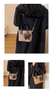 Close-up of retro bucket bag with dog charm, gold lettering, and dual-tone leather detail