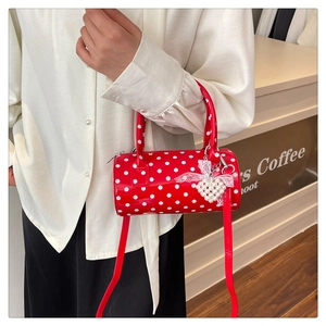 Détail du sac cylindre rouge à pois avec breloque cœur en perles et nœud en dentelle