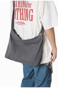 Detail of dark grey canvas shoulder bag featuring a large front pocket and washed fabric texture
