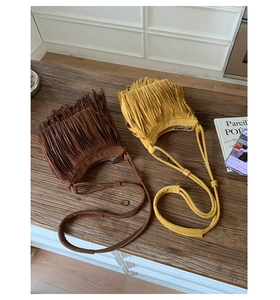 Flat lay of brown and yellow suede fringe shoulder bags on a vintage wooden table