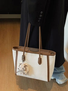Large white woven tote bag with brown leather handles and a plush bunny charm