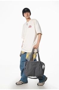 Detailed view of model holding a dark grey canvas bag with front pocket and handles