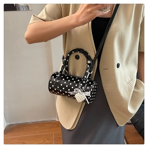 Gros plan du sac tonneau noir à pois avec pendentif cœur en perle et nœud en dentelle