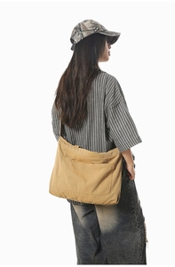 Detail view of khaki canvas tote bag featuring adjustable strap and front pocket
