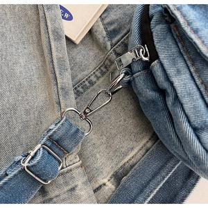 Close-up of silver metal hooks and zipper on the classic blue denim crossbody bag