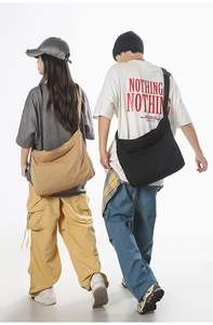 Detail view of large canvas messenger bags in black and khaki shown on models