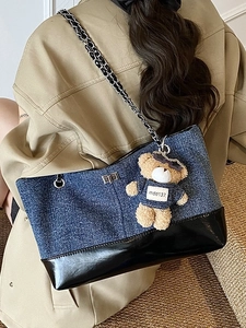 Contrast color denim and leather tote bag with silver chain strap and plush bear charm