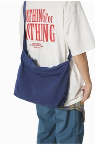 Detail of dark blue washed canvas crossbody bag with large front pocket and wide strap