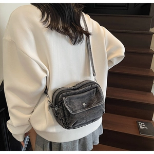 Detail of dark grey washed denim crossbody bag with flap pocket and adjustable strap