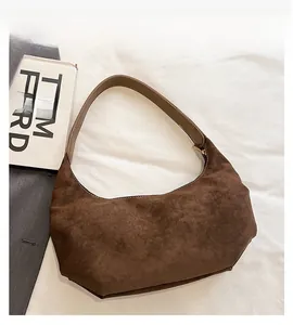 Detail view of brown suede hobo bag with leather strap and smooth metal zipper texture