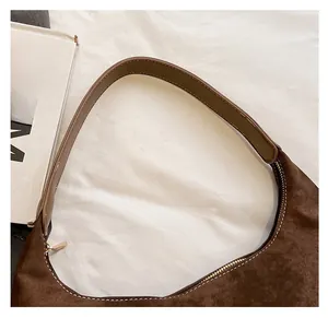 Close-up of brown suede hobo bag with leather strap and golden zipper detail