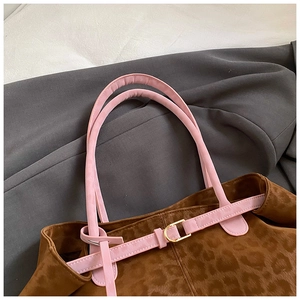 Detail of leopard print tote bag featuring pink handles and gold metal buckles
