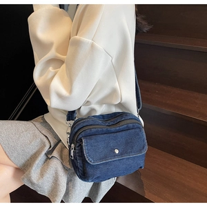 Deep blue denim crossbody bag with multiple zip compartments shown on lifestyle model