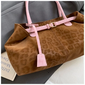 Close-up of leopard print tote bag texture with pink handles and golden metal buckle