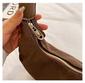 Macro detail of golden heart-shaped zipper puller on smooth dark brown leather handbag