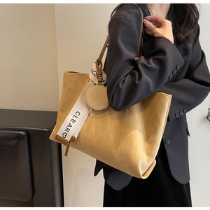 Detail of yellow tote bag featuring diamond pattern texture and wide logo canvas strap