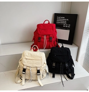 Tres mochilas de lona en colores rojo, blanco y negro con cordón y cierre de hebilla