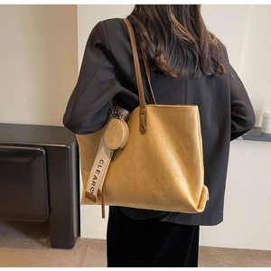 Detail of mustard yellow suede tote bag with diamond pattern and small round pouch