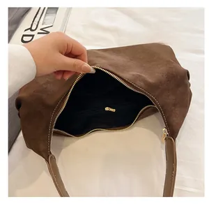Close-up of the brown suede dumpling bag interior with a zipper pocket and gold hardware