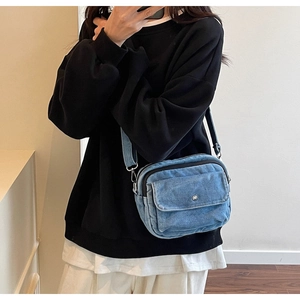 Mirror selfie showing the light blue denim crossbody bag with adjustable wide strap and pockets