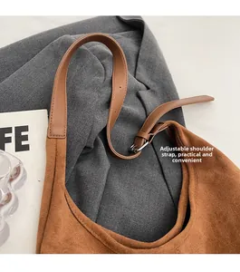 Détail de la bandoulière en cuir réglable avec boucle sur le sac seau en daim marron